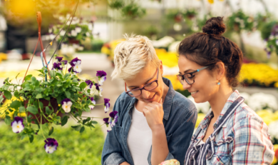 Zwei Frauen mit bunten Pflanzen in einem Gewächshaus