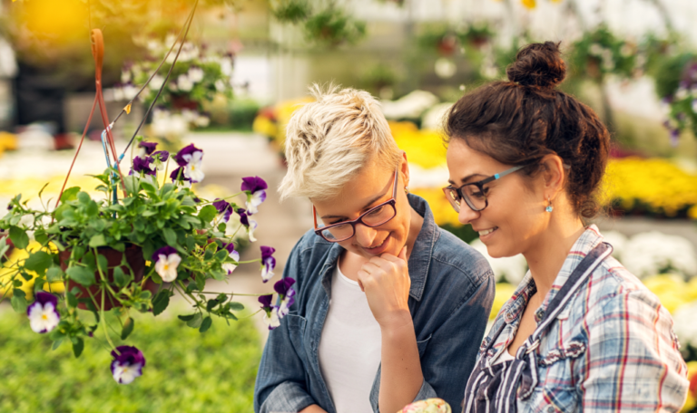 Zwei Frauen mit bunten Pflanzen in einem Gewächshaus