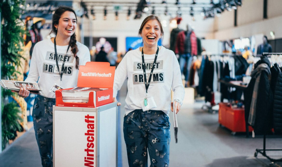 Zwei lachende Frauen mit dem TextilWirtschaft Magazin