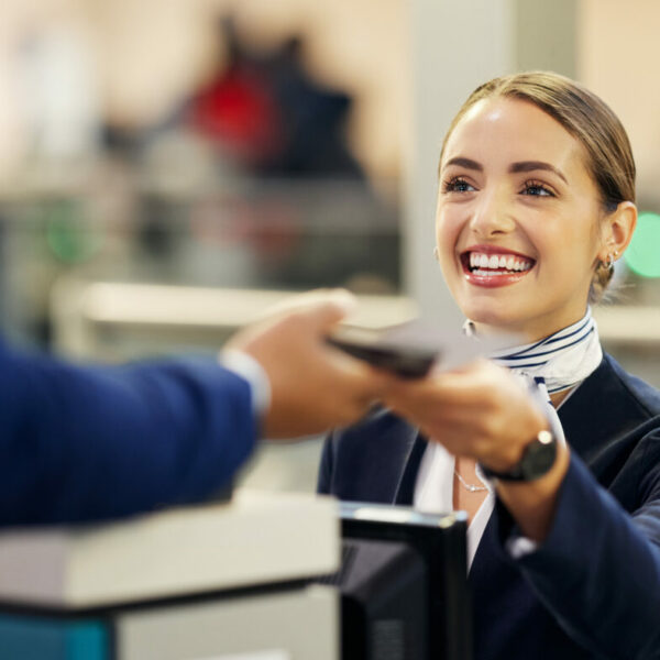 Lächelnde Frau an einem Flughafenschalter beim Check-in