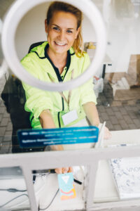 Lächelnde Frau mit Warnweste am Ticketschalter