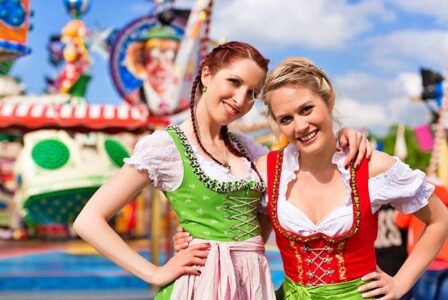 Zwei Promoterinnen im Dirndl vor einem Fahrgeschäft